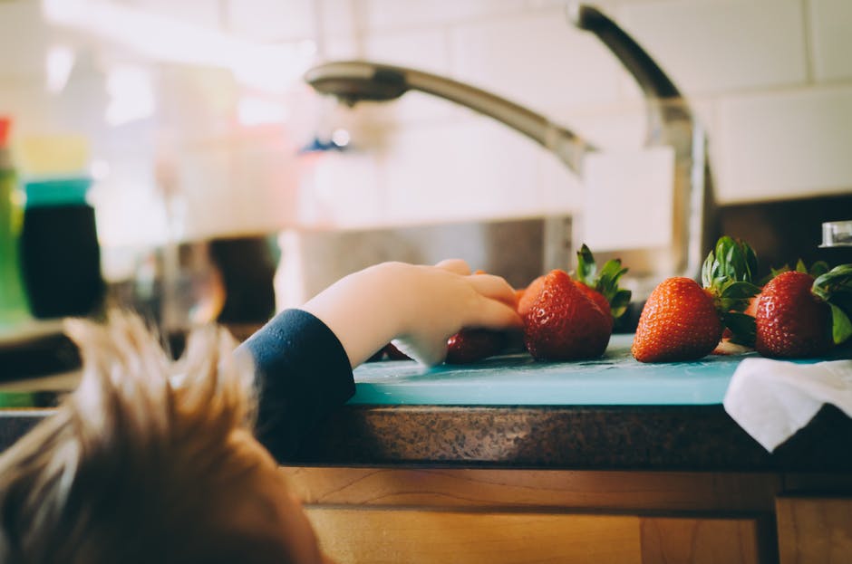 Child reaching for fruits on the kitchen counter