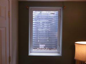 open basement window with a view to a metal well with fire escape ladder