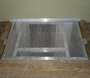 Egress aluminum grate with front tab and escape hatch.