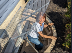 Woman exiting window well through hinged, sloped cover