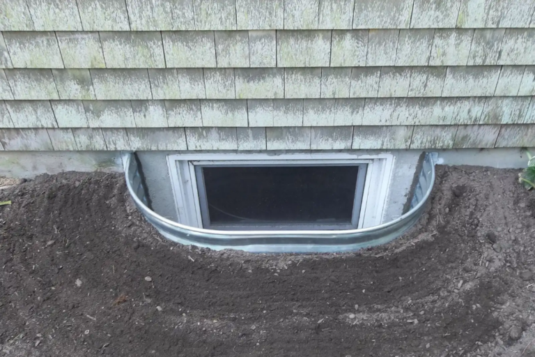 Elongated metal basement window well surrounded by soil