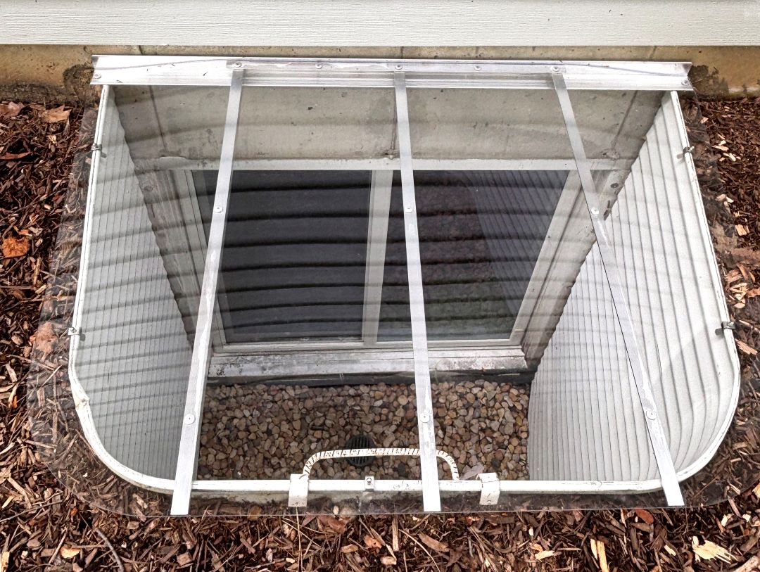 Sloped cover on egress metal well